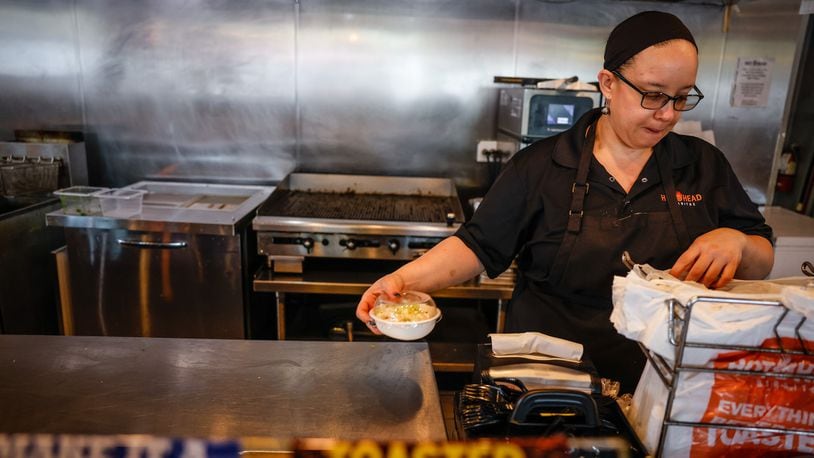 Manager of Hot Head Burritos on Brown St., Roxy Channels bags up food for a customer Monday June 13, 2022.  JIM NOELKER/STAFF