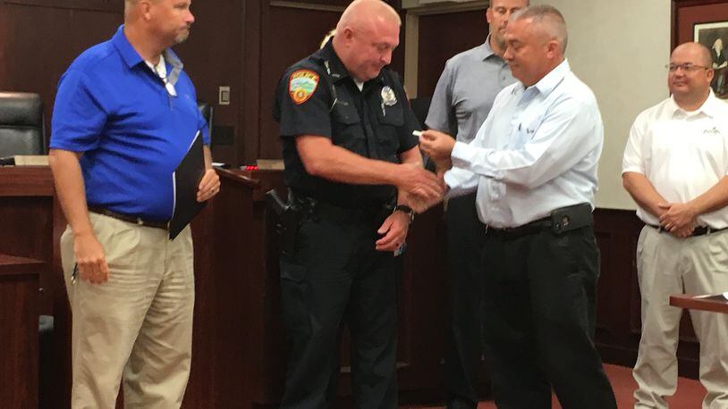 Franklin police Officer Dennis Shannon was recently presented a Meritorious Service Award for the saving the life of a three-year-old girl who was choking on a hot dog in March. At right is Mayor Todd Hall, Shannon, police Chief Russell Whitman, left. ED RICHTER/STAFF