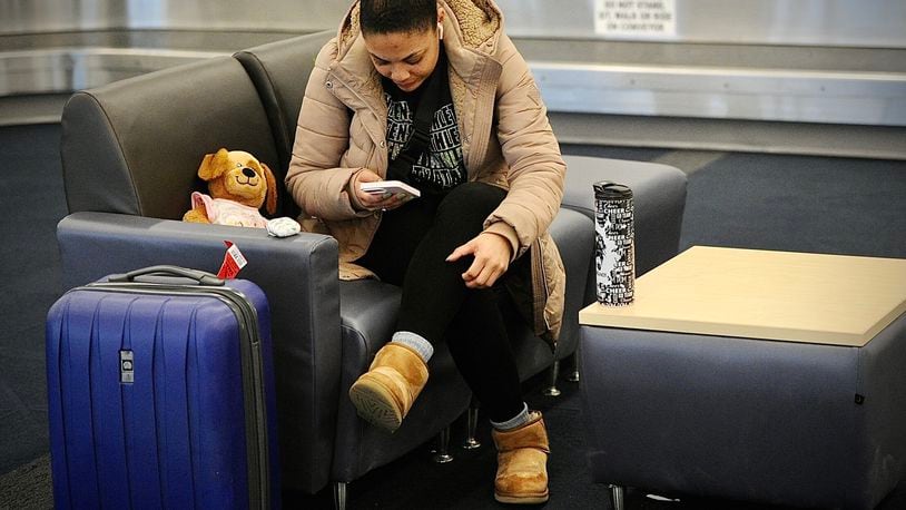 Shayla Moore waits at the Dayton International Airport for her mother to pick her up after her flight was canceled early Wednesday morning on Jan. 11, 2023. MARSHALL GORBY\STAFF