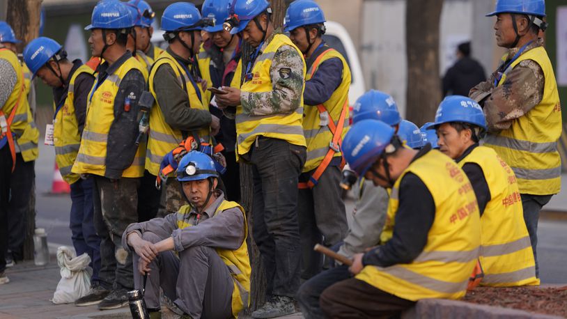 Workers wait for transport outside a construction site in Beijing, Tuesday, April 9, 2024. China's Finance Ministry has denounced a report by Fitch Ratings that kept its sovereign debt rated at A+ but downgraded its outlook to negative, saying in a statement that China's deficit is at a moderate and reasonable level and risks are under control. (AP Photo/Ng Han Guan)