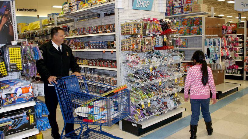 West Chester Twp. Police Chief Joel Herzog hurries to keep up with one of two dozen needy children who participated in the department’s annual Christmas “Kids ‘N Cops” shopping event. The recent event at sponsoring store Meijer on Tylersville Road including two dozen children being helped by police officers. CONTRIBUTED