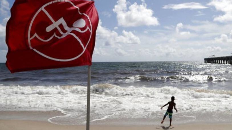 A boy plays on the beach in Lake Worth, Florida, on Saturday as a no-swimming flag flaps in the breeze.