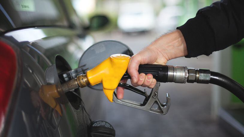 Hand of man fueling up a vehicle with a yellow gas pump (stock photo).
