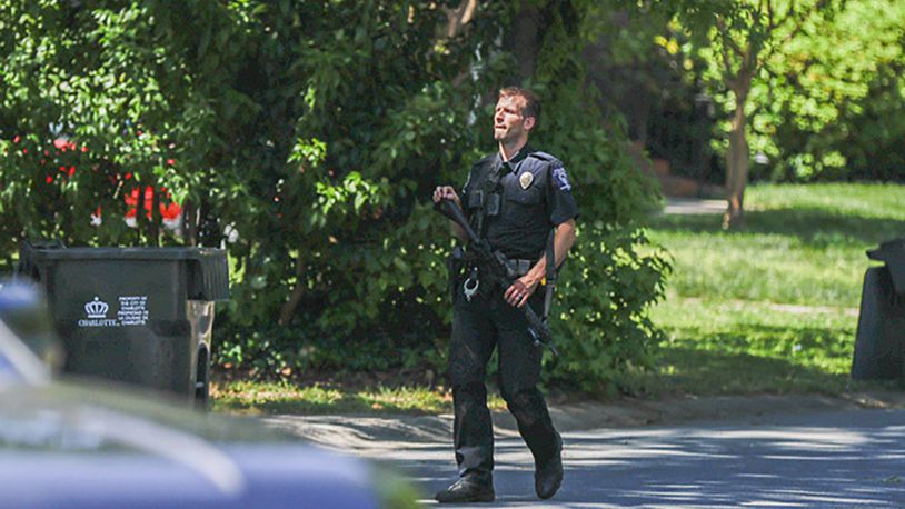 A Charlotte Mecklenburg police officer carries a gun as he walks in the neighborhood where an officer-involved shooting took place in Charlotte, N.C., Monday, April 29, 2024. Police in North Carolina say numerous law enforcement officers conducting a task force operation have been struck by gunfire in Charlotte. (AP Photo/Nell Redmond)