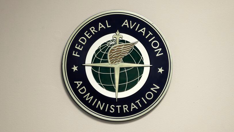 FILE - A Federal Aviation Administration sign hangs in the tower at John F. Kennedy International Airport in New York, March 16, 2017. Congressional negotiators have agreed on a $105 billion bill designed to improve the safety of air travel after a series of close calls between planes at the nation’s airports. (AP Photo/Seth Wenig, File)