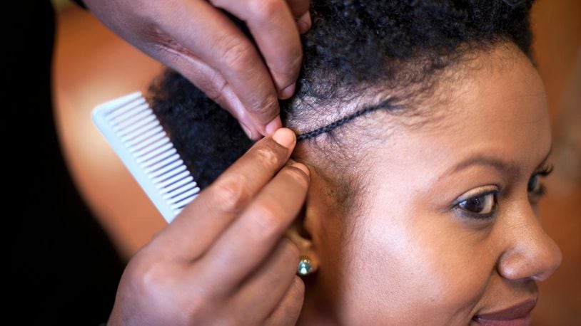 Hair stylist braiding woman's hair