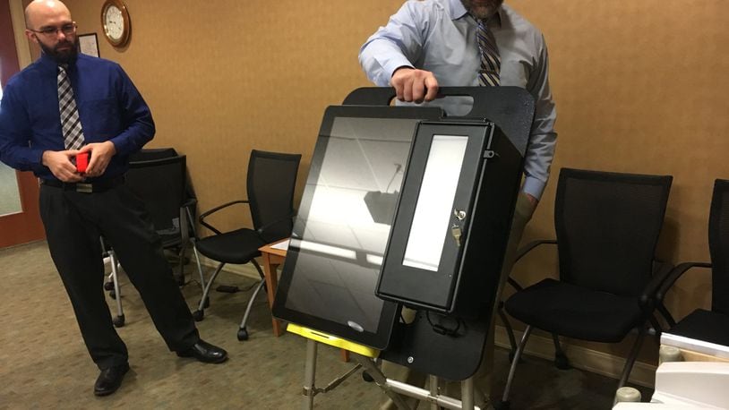 Butler County Board of Elections board member Todd Hall reviews an electronic voting machine on Monday morning, at the board office in Princeton Road in Hamilton. MICHAEL D. PITMAN/STAFF