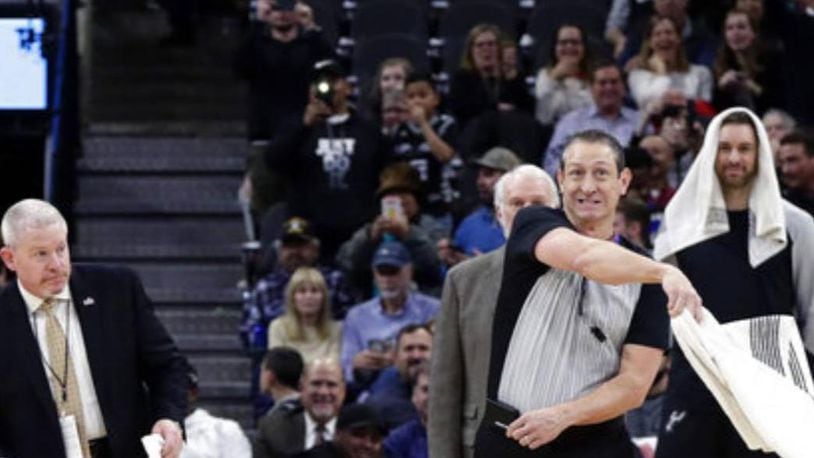 An official uses a towel to swat at a bat during the first quarter of Thursday's NBA game in San Antonio.