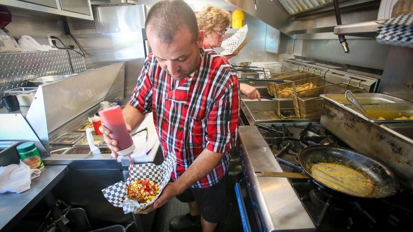 Vitor Abrue of the Urban Bistro food truck puts the finishing touches on a Pork'n'Cheese during the  Union Centre Food Truck Rally, Aug. 11, in West Chester Twp. GREG LYNCH / STAFF