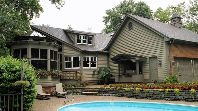 A screen-enclosed porch divides the back of the house. One side has an in-ground swimming pool surrounded by a paver-brick patio. The other side has a semi-covered paver patio with pathways to the spring-fed pond and waterfalls.