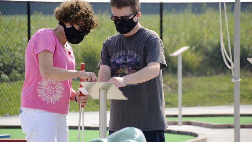 Terry Zornow, left, of Fairfield, helps her son, Bobby Zornow, 25, fill out the mini golf score card on Monday, Aug. 24, 2020, at the Joe Nuxhall Miracle League on Groh Lane in Fairfield. Bobby is autistic. MICHAEL D. PITMAN/STAFF