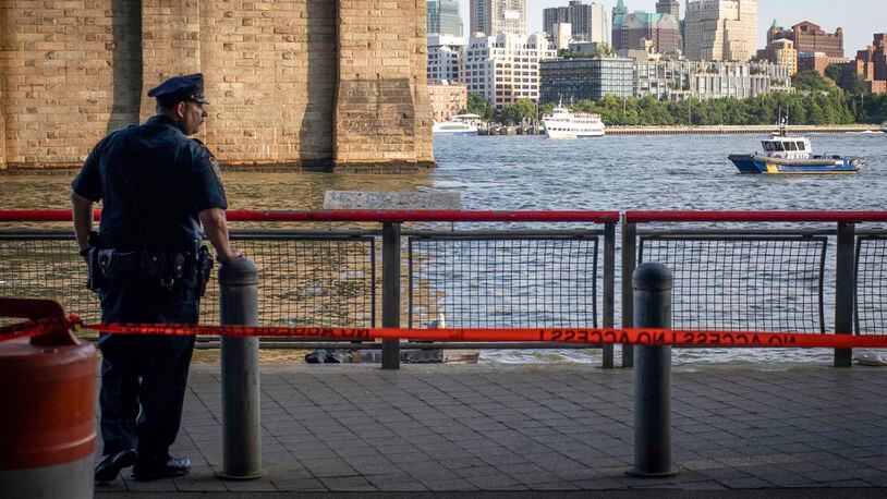 FILE - In this Aug. 5, 2018, file photo, a New York Police Department officer stands guard as authorities investigate the death of a baby boy who was found floating in the East River near the Brooklyn Bridge in the Manhattan borough of New York. A Bronx father hopped a plane to Thailand after carrying his dead 7-month-old baby around New York City in a backpack and tossing the boy's body into the river and other tourist hotspots, police said Wednesday. (AP Photo/Robert Bumsted, File)