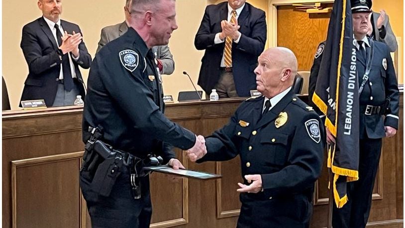 Officer Dan Fry, left, accepts the Medal of Valor Award from Police Chief Jeff Mitchell at Tuesday's Lebanon City Council meeting. Fry, who serves as a school resource officer, is also a member of the Warren County SWAT team. He was nominated for the award for his actions during summer hostage rescue situation in Mason which saved a woman's life. ED RICHTER/STAFF