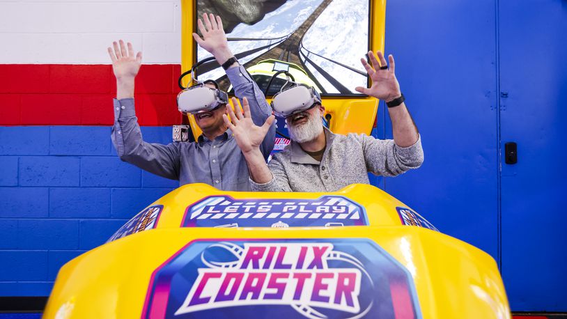 Jeff Archiable, with Hamilton Vision Commission, left, and Steve Colwell, with TVHamilton, ride a virtual roller coaster in the new expansion at Pinball Garage in Hamilton. The new room features more high-end arcade games, virtual roller coaster and more. NICK GRAHAM/STAFF