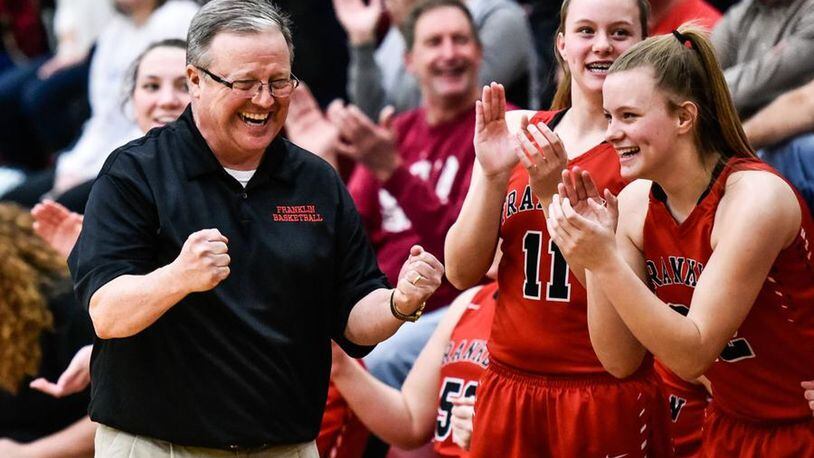 Franklin coach John Rossi starts to enjoy his team’s Division II sectional championship with Kristin Earles (11) and Madison Earles (22) late in Monday night’s game against Monroe at Lebanon. NICK GRAHAM/STAFF