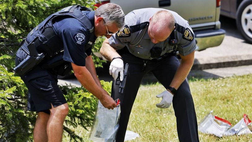 Police place a gun found in a grassy area of an apartment complex into an evidence bag Wednesday, June 22, 2022, in Springboro following a chase that began in Franklin. NICK GRAHAM/STAFF