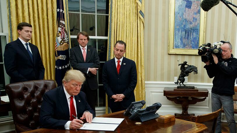 President Donald Trump signs his first executive order in the Oval Office of the White House, Friday, Jan. 20, 2017, in Washington. (AP Photo/Evan Vucci)