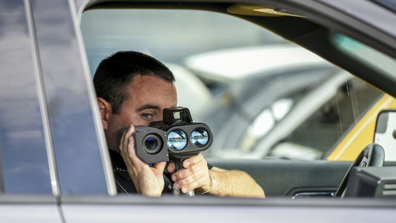 In this file photo, New Miami Police Officer Mark Bennett uses their Lidar photo laser speed enforcement camera along US 127 in New Miami. NICK GRAHAM/STAFF
