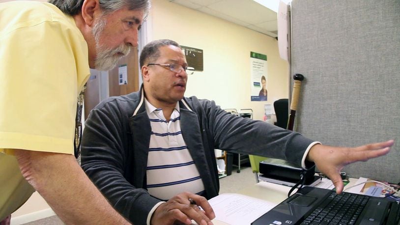 Affordable Care Act Navigator Ron Irvine, left, helps Dayton resident Kenneth Flowers, 56, get reconnected to the government website after Flowers got disconnected on Monday, the deadline for signing up for government healthcare TY GREENLEES / STAFF