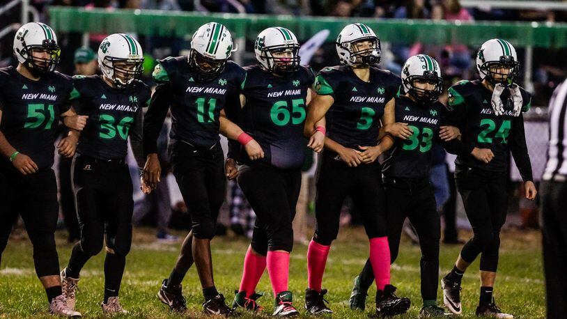 New Miami seniors lock arms as they make their way out for the coin toss before their game against Cincinnati Country Day Friday, Oct. 25, 2019 at New Miami High School. New Miami defeated Cincinnati Country Day 34-6 and is 9-0 for the first time in school history. NICK GRAHAM/STAFF