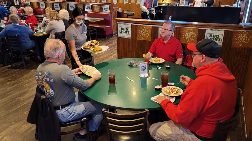 Waitress Mya Hogeback serves food to Bruce Taylor, left, Brian Taylor and Rod McGaha, right, Thursday at Putters Sports Grill in Liberty Twp. Owner Jan Collins closes the restaurant every Monday to save on overhead. NICK GRAHAM/STAFF