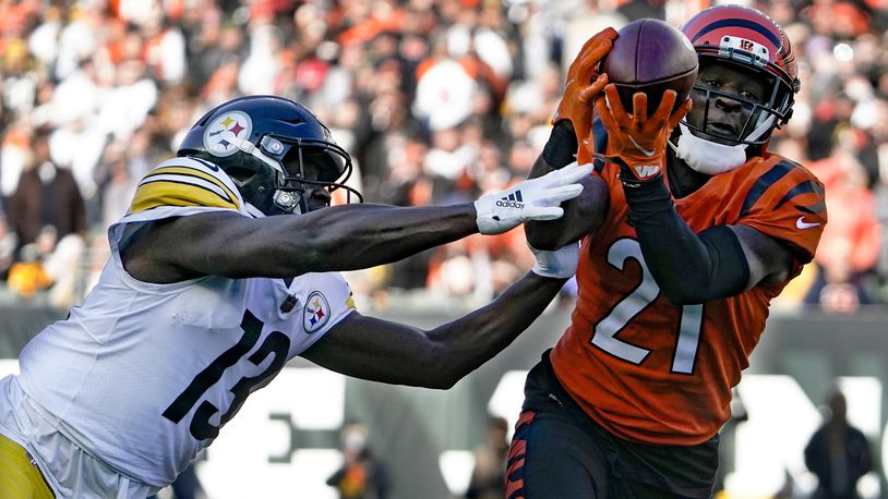 Cincinnati Bengals cornerback Mike Hilton (21) makes an interception of a pass intended for Pittsburgh Steelers wide receiver James Washington (13) during the first half of an NFL football game, Sunday, Nov. 28, 2021, in Cincinnati. Hilton returned the ball for a touchdown. (AP Photo/Jeff Dean)