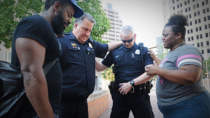 Officer Will Davis, Sergeant Chad Knight, Natasha Hunter and a man who wished not to be identified, pray together at Courthouse Square after a foot washing ceremony. Marshall Gorby/Staff photo