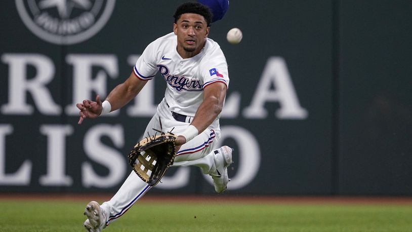Texas Rangers left fielder Bubba Thompson lunges for the ball hit for a double by Kansas City Royals' Vinnie Pasquantino during the fourth inning of a baseball game, Tuesday, April 11, 2023, in Arlington, Texas. (AP Photo/Tony Gutierrez)