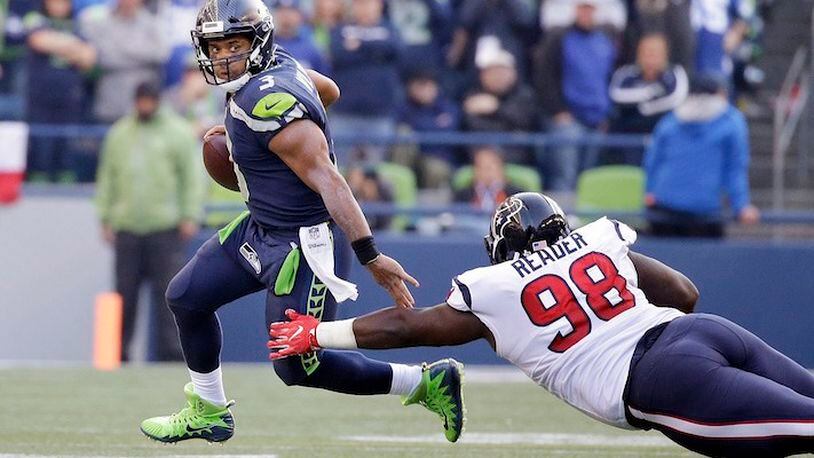 Seattle Seahawks quarterback Russell Wilson, left, scrambles away from Houston Texans' D.J. Reader in the second half of an NFL football game, Sunday, Oct. 29, 2017, in Seattle. The Seahawks won 41-38. (AP Photo/Elaine Thompson)