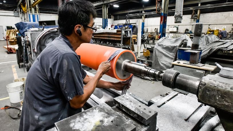 Hoa Dao polishes a roller to specification at Cent-Roll Products Inc. in Fairfield. The company makes is hiring for grinding positions and several temporary laborer positions. NICK GRAHAM/STAFF