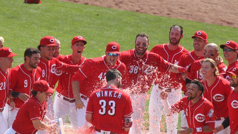 The Reds greet Jesse Winker at home plate after his game-winning two-run home run in the 13th inning against the Rockies on Thursday, June 7, 2018, at Great American Ball Park in Cincinnati. David Jablonski/Staff