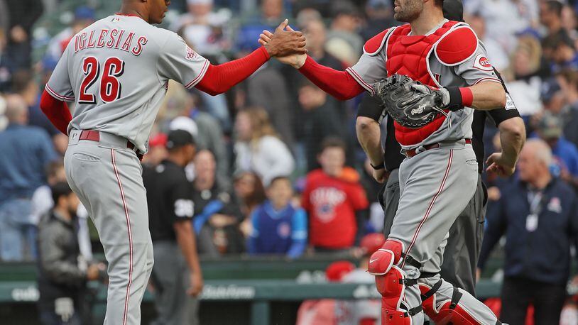 CHICAGO, ILLINOIS - MAY 24: Raisel Iglesias #26 of the Cincinnati Reds
is congratulated by Tucker Barnhart #16 after pitching for a save in the 9th inning against the Chicago Cubs at Wrigley Field on May 24, 2019 in Chicago, Illinois. The Reds defeated the Cubs 6-5. (Photo by Jonathan Daniel/Getty Images)