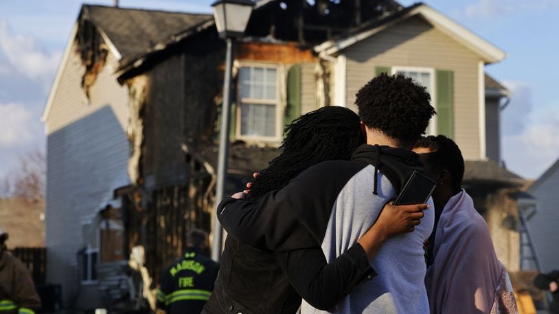 Family members embrace as they look at their house after a fire Friday, Feb. 23, 2024, on Marcia Drive in Trenton. NICK GRAHAM/STAFF
