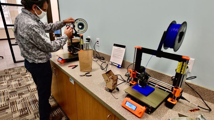 A staff member feeds material to start a project on a 3D printer Tuesday at the Lane Library Community Technology Center in downtown Hamilton. NICK GRAHAM/STAFF