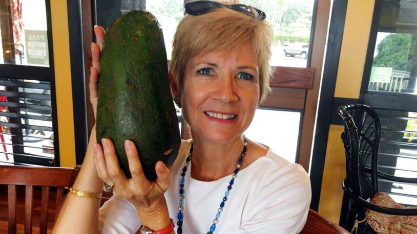FILE - In this Nov. 28, 2017 file photo provided by Mary Lou Knurek, Pamela Wang poses for a photo in Kealakekua, Hawaii, with an avocado she found while on a walk. Guinness World Records has confirmed that Wang found the world's heaviest avocado, weighing  5-pound, 3.6-ounce (2.4-kilogram).  (Mary Lou Knurek via AP, File)