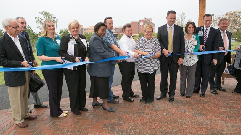 Atrium Medical Center executives celebrate the completion of a paved walking trail surrounding the hospital. The path loops through gardens surrounding the hospital in Middletown. WAYNE BAKER/STAFF