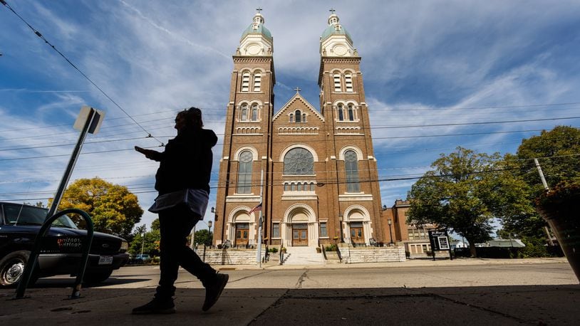 A person Thursday walks in front of St. Marys Catholic Church on Xenia Avenue. Citing pressures from a shrinking number of priests and declining membership, the Archdiocese of Cincinnati today released its draft plan to reorganize parishes across Southwestern Ohio.