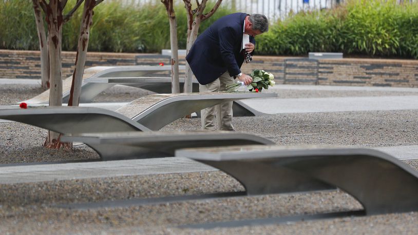 A man stops to lay flowers on one of the benches at the National 9/11 Pentagon Memorial before the start of the September 11th Pentagon Memorial Observance at the Pentagon on the 17th anniversary of the September 11th attacks, on Tuesday, Sept. 11, 2018. (AP Photo/Pablo Martinez Monsivais)