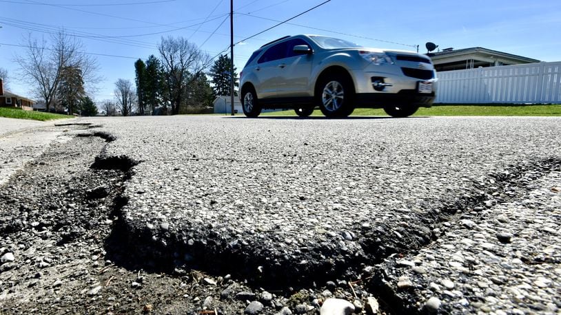 A vehicle travels by a rough patch of W. Roger Drive Wednesday, April 3, 2019 in Trenton. The new 10.5-cent-per-gallon gas tax increase has allowed Trenton to reduce a road levy request from up to 6 mills to 3.9 mills. NICK GRAHAM/STAFF