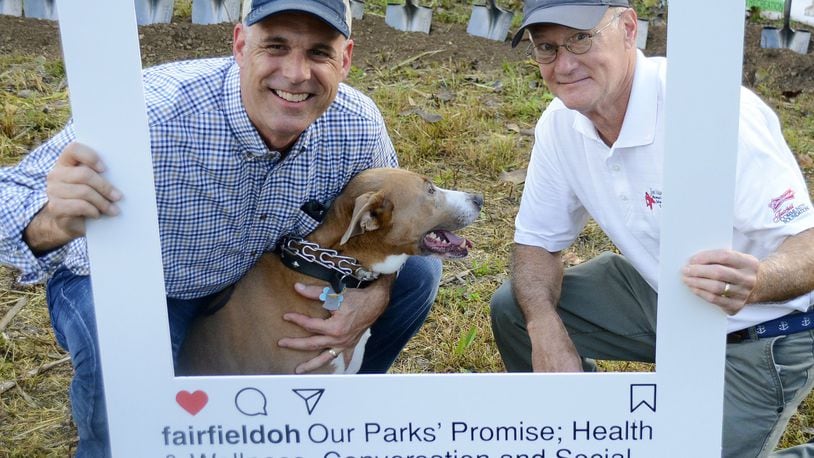 The city of Fairfield is a bit behind schedule because of the soggy winter and early spring, but the 6.5-acre dog park on River Road in Fairfield, just south of Marsh Park, will open later this year. Pictured are Fairfield City Manager Mark Wendling, left, and Fairfield Law Director John Clemmons posing for a promotional Instagram cutout promoting the dog park. MICHAEL D. PITMAN/FILE