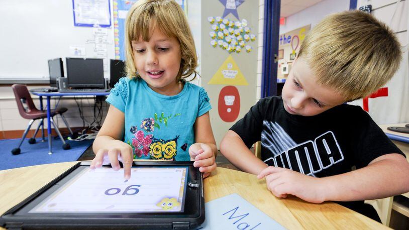Monroe Local Schools starts a new school year Wednesday, Aug. 16. In this 2012 file photo, kindergartners at Monroe Primary School use an iPad to learn letters and words. NICK GRAHAM/2012