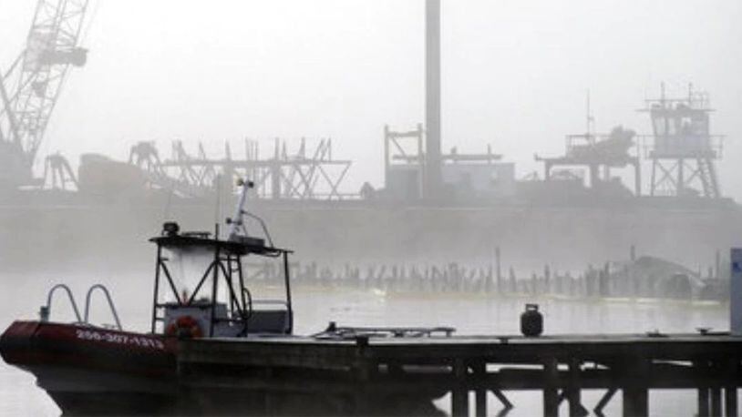 A salvage crane shrouded in fog rises above a barge in a creek near the Tennessee River at the scene of a fatal marina fire at Scottsboro, Alabama. Authorities identified the victims Wednesday.