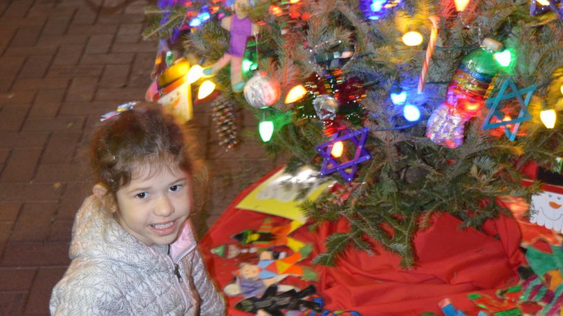 The Kiwanis Club’s decorated tree was ringed by figures of children colored by Kramer kindergarten students. Emmerson Byrd points to her art effort in the project. CONTRIBUTED/BOB RATTERMAN