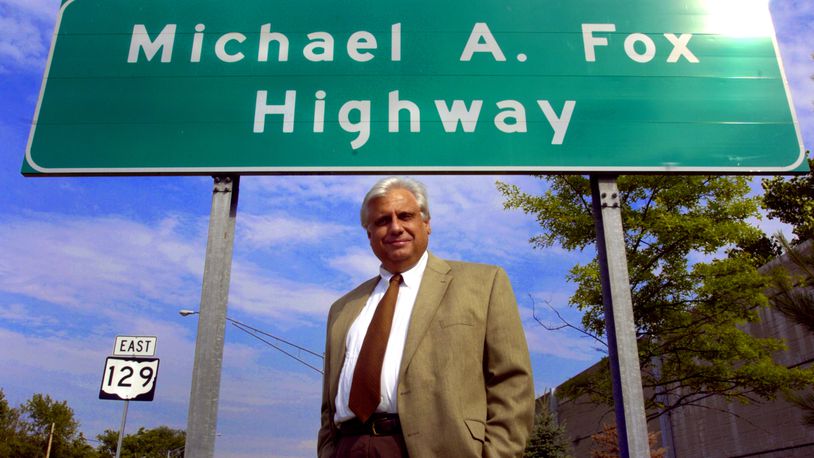 Mike Fox poses for a photo under a sign marking the Michael A. Fox Highway, Wednesday, June 9, 2004, in Hamilton, Ohio. (AP Photo/Glenn Hartong)