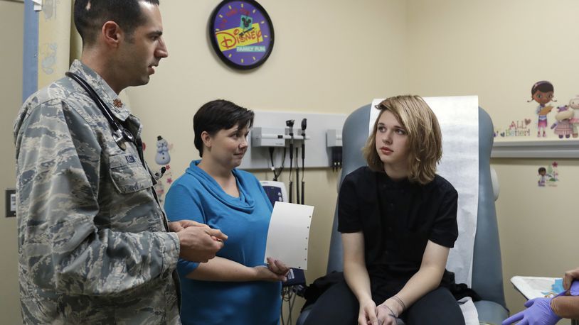 In this Sept. 7, 2016, photo, Dr. David Klein, an Air Force Major and chief of adolescent medicine at Fort Belvoir Community Hospital, left, speaks with Amanda Brewer and her daughter Jenn Brewer, 13, during the teenager's regular monthly doctors appointment for monitoring of her treatment at the hospital in Fort Belvoir, Va. Brewer is transitioning from male to female. Starting Oct. 3, the military’s health insurance will cover transgender-related services that include hormone therapy and supportive counseling.(AP Photo/Jacquelyn Martin)
