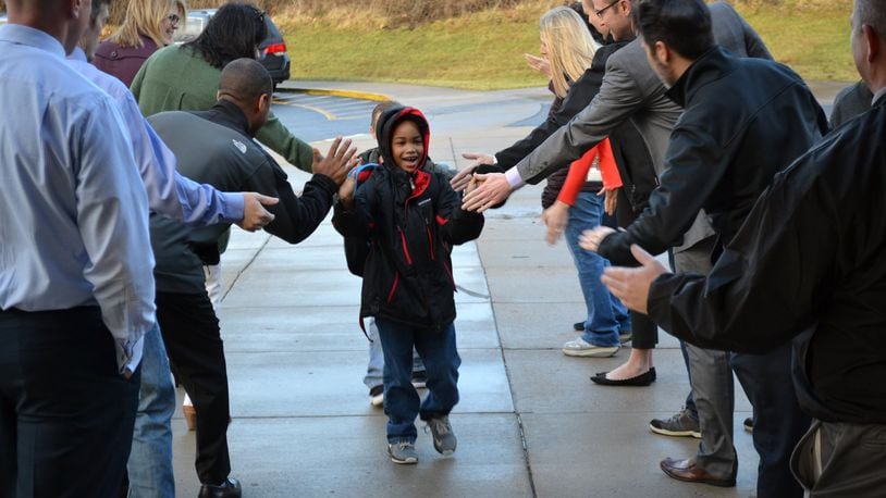 Brendyn Carter - a kindergarten student at Lakota’s Shawnee Early Childhood Center - is greeted arriving to school as part of the school system’s new fanfare events. Adult residents, school staffers and local business people are invited to form a greeting tunnel to encourage students and show them the importance of education. CONTRIBUTED