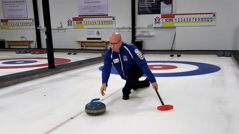 Jonathan Penney, president of the Cincinnati Curling Club, slides a stone down the ice toward concentric circles known as “the house” in a demonstration of the sport. The Cincinnati Curling Club is opening the first dedicated curling only facility in the tri-state area at 5150 Duff Drive in West Chester Twp. The former warehouse includes three lanes. ERIC SCHWARTZBERG/STAFF