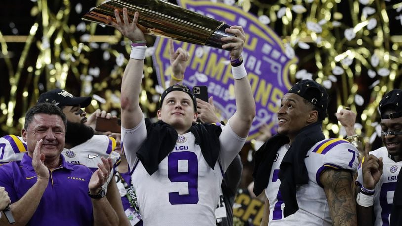 FILE - In this Monday, Jan. 13, 2020, file photo, LSU quarterback Joe Burrow holds the trophy as safety Grant Delpit looks on after LSU defeated Clemson 42-25 in the NCAA College Football Playoff national championship game, in New Orleans. Imagine if a pandemic had shortened or wiped out that last, golden season for Burrow, who won the Heisman Trophy and led LSU to the national championship. Would he still have emerged as the first overall NFL draft pick? (AP Photo/Sue Ogrocki, File)