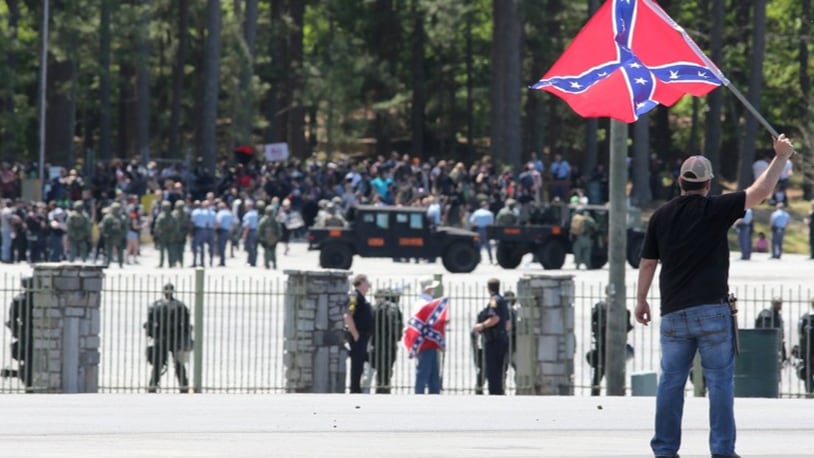 Joseph Andrews, one of a small group with the Rock Stone Mountain rally, waves a confederate battle flag towards a mass of counter-protesters more than 100 yards away at Stone Mountain Park on Saturday afternoon April 23, 2016 where a white power protest and two counter protests were scheduled.