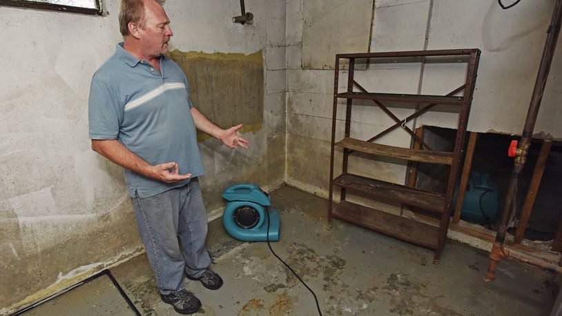 Mike Seeley stood in his Cereal Avenue basement in early June, several days after an intense rain flooded it. Much of the drywall that was soaked with water had been removed and he was using 10 industrial fans, a dehumidifier and an air cleaner to dry out the cellar. NICK GRAHAM/STAFF